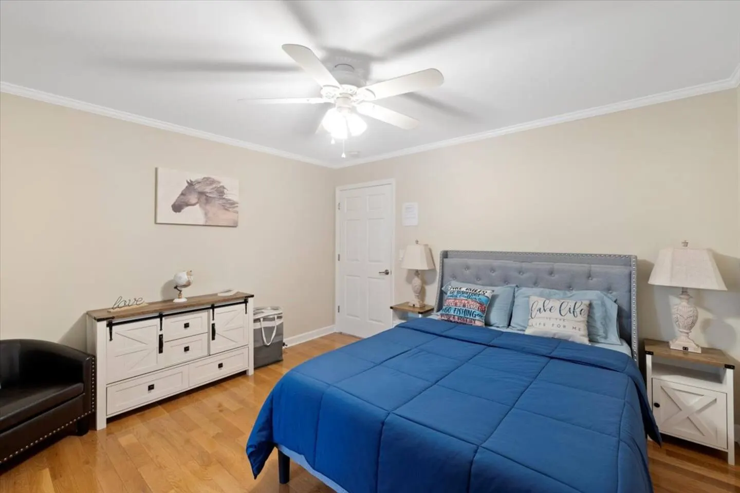 Queen bedroom with neutral tones, upholstered headboard, and lake-themed accents